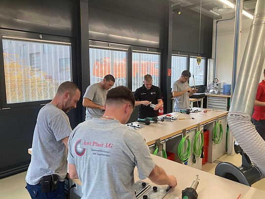 Gruppe von Teilnehmern führt praktische Schweißübungen an Werkstücken durch.
